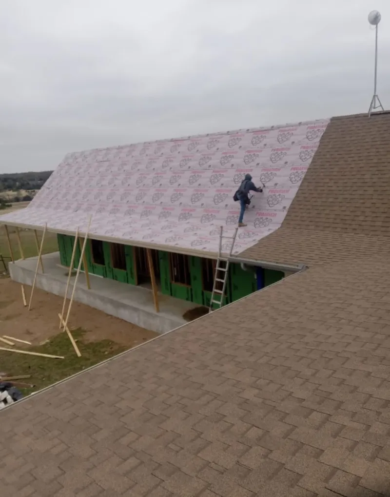 Worker preparing underlayment for a metal roof installation in Raymondville
